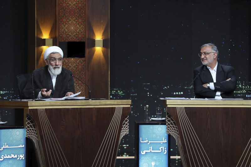 In this picture released by the Iranian state-run TV, IRIB, presidential candidate in the June 28 election Mostafa Pourmohammadi, a former Minister of Justice, left, speaks as candidate Alireza Zakani, who is Tehran mayor, listens during a debate at the TV studio in Tehran, Iran, Thursday, June 20, 2024. (Morteza Fakhri Nezhad/IRIB via AP)