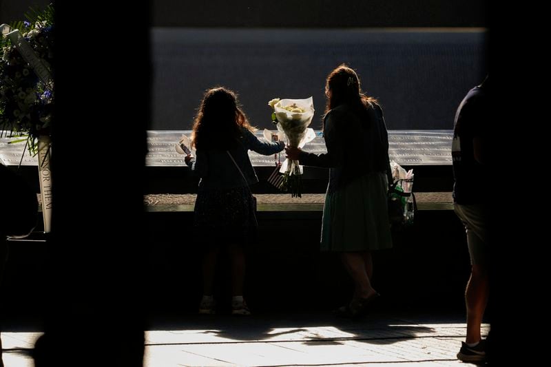 People place flowers on the bronze parapets that ring the reflecting pools during the 9/11 Memorial ceremony on the 23rd anniversary of the Sept. 11, 2001 terror attacks, Wednesday, Sept. 11, 2024, in New York. (AP Photo/Pamela Smith)