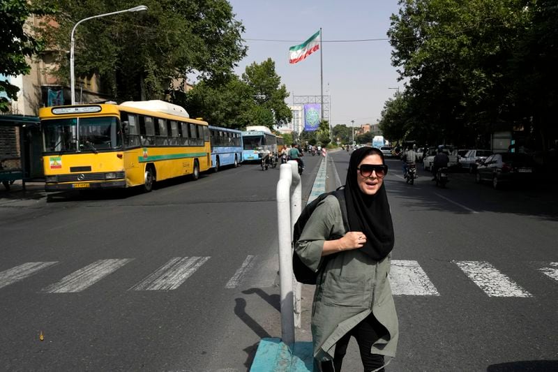 A woman crosses a street in downtown Tehran, Iran, Saturday, June 29, 2024. Iran will hold a runoff presidential election to replace the late hard-line President Ebrahim Raisi after an initial vote saw the top candidates not secure an outright win in the lowest turnout poll ever held in the Islamic Republic by percentage. (AP Photo/Vahid Salemi)
