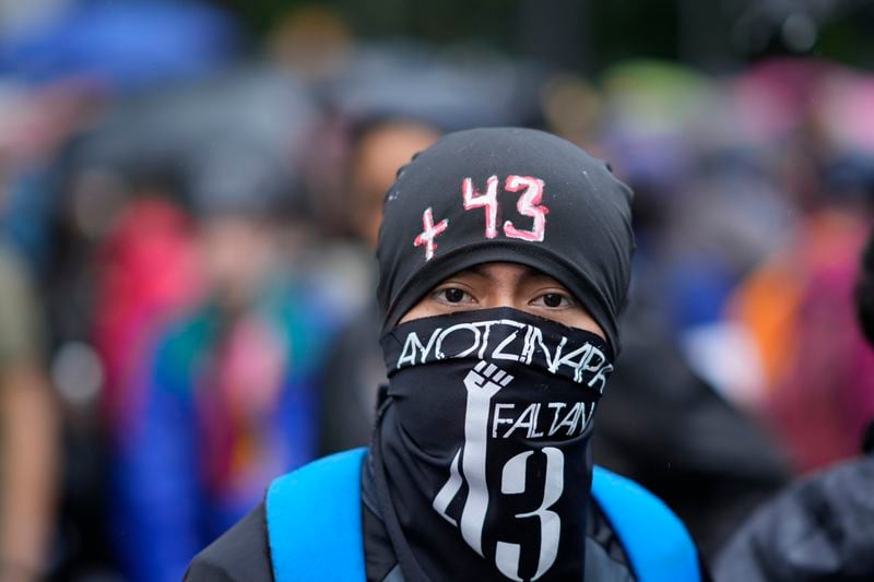 A masked youth takes part in a demonstration marking the 10-year anniversary of the disappearance of 43 students from an Ayotzinapa rural teacher's college, in Mexico City, Thursday, Sept. 26, 2024. (AP Photo/Eduardo Verdugo)