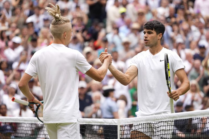 Carlos Alcaraz, right, of Spain is congratulated Mark Lajal of Estonia following their first round match at the Wimbledon tennis championships in London, Monday, July 1, 2024. (AP Photo/Alberto Pezzali)