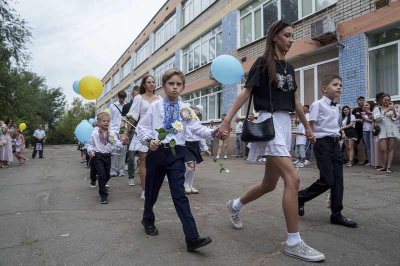 First-grades walk to the traditional ceremony for the first day of school in Zaporizhzhia, Ukraine, Sunday Sept. 1, 2024. Zaporizhzhia schoolchildren celebrated the traditional first day of school near the frontline. With the front just 40 kilometers away, the war is never far from the minds of teachers and families. (AP Photo/Evgeniy Maloletka)