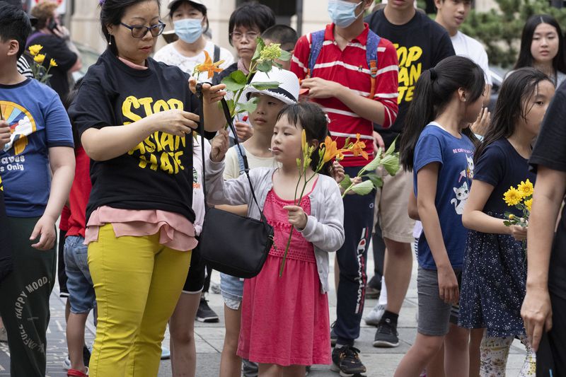 Children with flowers attend a remembrance ceremony for Vincent Chin in Chinatown, Sunday, June 23, 2024, in Boston. Over the weekend, vigils were held across the country to honor the memory of Chin, who was killed by two white men in 1982 in Detroit. (AP Photo/Michael Dwyer)