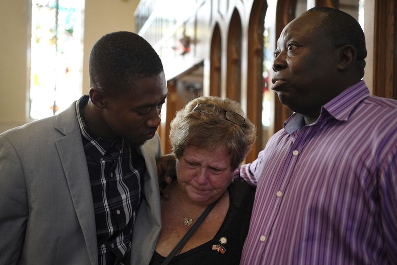 St Raphael Catholic church parishioners, Berthing Jean Philippe, left, Casey Kelly Rollins and Patrick Joseph embrace after a service in support of the Haitian in Springfield, Ohio, Sunday, Sept. 15, 2024. (AP Photo/Luis Andres Henao)