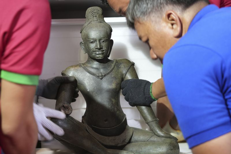 Cambodian museum staff members place an artifact statue as it returned from U.S to Cambodia, before an official ceremony at the Cambodian National Museum in Phnom Penh Cambodia, Thursday, July 4, 2024. Cambodia on Thursday officially organized a welcome ceremony for the arrival of more than a dozen rare Angkor era sculptures from New York's Metropolitan Museum of Art that were tied to an art dealer and collector accused of running a huge antiquities trafficking network out of Southeast Asia. (AP Photo/Heng Sinith)