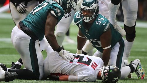 Falcons quarterback Matt Ryan lays on the turf taking a hard sack by Philadelphia Eagles defensive tackle Javon Hargrave (left) and defensive end Brandon Graham late in the fourth quarter Sunday, Sept. 12, 2021, at Mercedes-Benz Stadium in Atlanta. (Curtis Compton / Curtis.Compton@ajc.com)