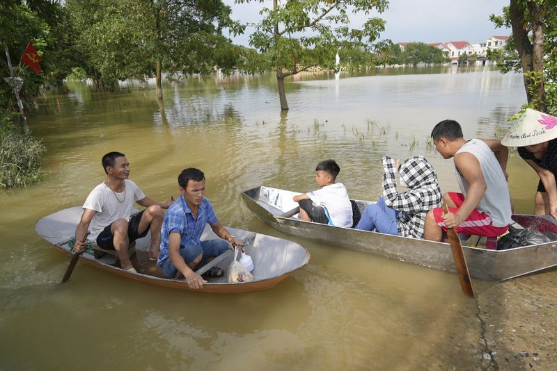 People sit on a boat to get to their flooded homes in the aftermath of Typhoon Yagi in An Lac village, Hanoi, Vietnam Friday, Sept. 13, 2024. (AP Photo/Hau Dinh)