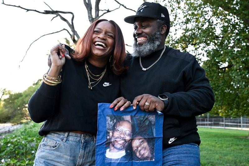 Ferguson activist Brittany Packnett-Cunningham, left, and her husband Reggie Cunningham, pose for an image while holding a handkerchief with picture of her father Rev. Ronald Packnett and Brittany, Saturday, Sep. 7, 2024, in Mount Rainier, Md. (AP Photo/Terrance Williams)