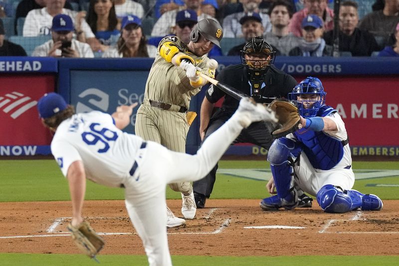 San Diego Padres' Jake Cronenworth, second from left, hits a two-run home run as Los Angeles Dodgers starting pitcher Landon Knack, left, washes along with catcher Will Smith, right, and home plate umpire Tripp Gibson during the second inning of a baseball game, Tuesday, Sept. 24, 2024, in Los Angeles. (AP Photo/Mark J. Terrill)