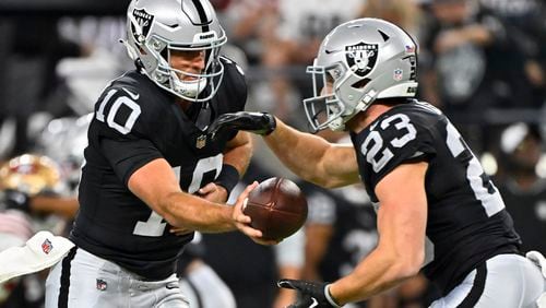 Las Vegas Raiders quarterback Nathan Peterman (10) hands off the ball to running back Dylan Laube (23) against the San Francisco 49ers during the first half of an NFL preseason football game, Friday, Aug. 23, 2024, in Las Vegas. (AP Photo/David Becker)