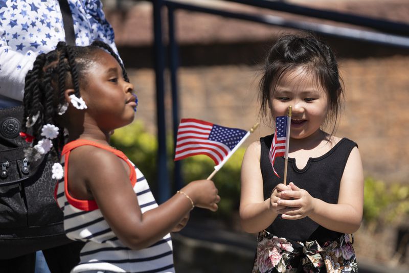 Elizabeth Weiter, 5, right, looks at a American flag as Camree Lee, 3, looks towards the parade during the annual Fourth of July Parade in Alameda, Calif. on Thursday, July 4, 2024. (Minh Connors/San Francisco Chronicle via AP)