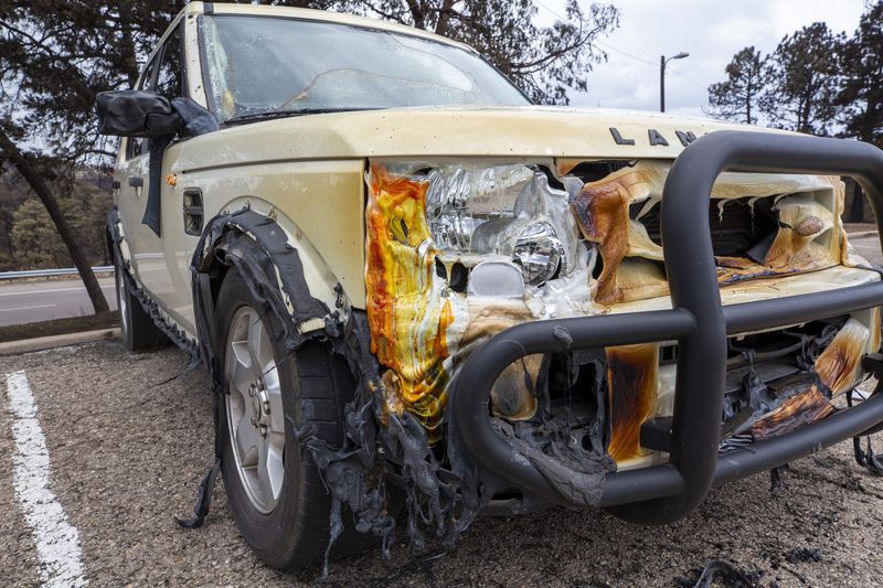 The partially melted body of a car sits in the parking lot of the Swiss Chalet Hotel after it was destroyed by the South Fork Fire in the mountain village of Ruidoso, N.M., Saturday, June 22, 2024. (AP Photo/Andres Leighton)