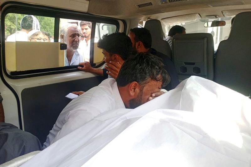 Family members react next to the body of a woman, who was killed when a passenger bus fell into a ravine, at a hospital in Kahuta, Pakistan, Sunday, Aug. 25, 2024. (AP Photo/Mohammad Yousaf)