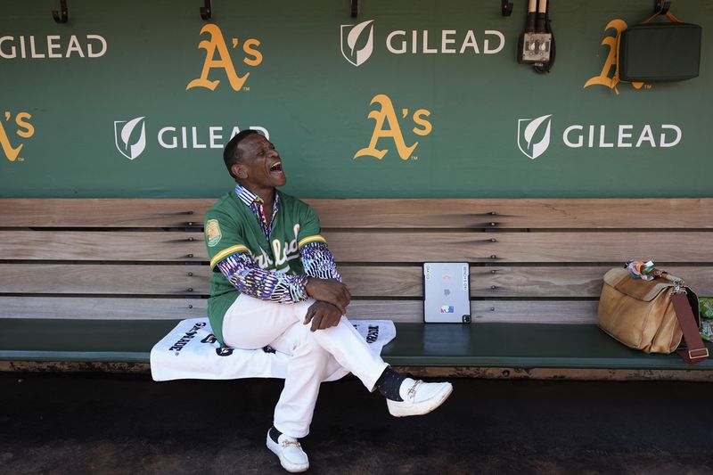 Former baseball player Rickey Henderson laughs as he sits in the dugout before a baseball game between the Oakland Athletics and the Texas Rangers, Thursday, Sept. 26, 2024, in Oakland, Calif. (AP Photo/Godofredo A. Vásquez)