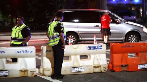 July 4, 2019 Atlanta: Atlanta police officers man a barricade at 10th Street and Monroe Drive N.E. as roads are shut down for the AJC Peachtree Road Race on Thursday, July 4, 2019, in Atlanta.  Curtis Compton/ccompton@ajc.com