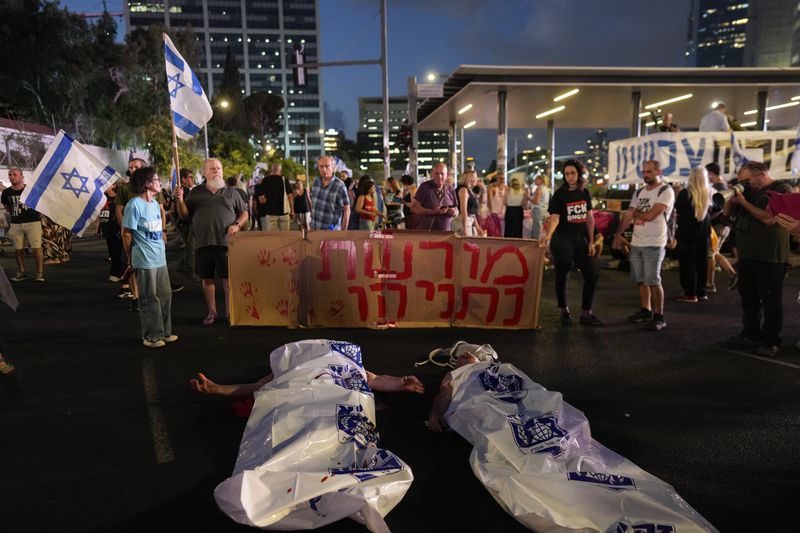 Demonstrators lie on the ground in white plastic bags simulating dead bodies, take part in a protest against Israeli Prime Minister Benjamin Netanyahu's government in Tel Aviv, Israel, Saturday, Aug. 31, 2024. (AP Photo/Ohad Zwigenberg)