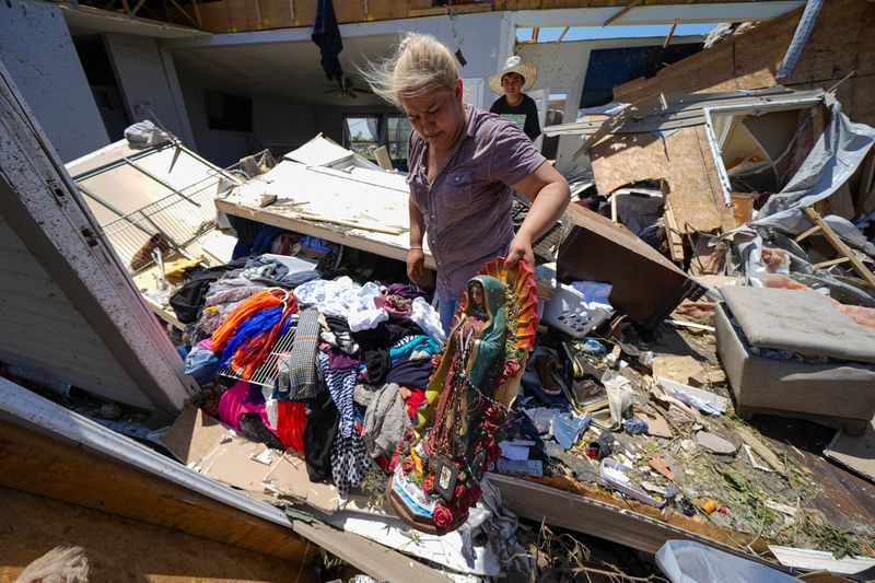 Juana Landeros, who rode out deadly tornado with her husband and her 9-year-old son when it rolled through the previous night, salvages a Guadalupe Virgin statue from her destroyed home, Sunday, May 26, 2024, in Valley View, Texas. Powerful storms left a wide trail of destruction Sunday across Texas, Oklahoma and Arkansas after obliterating homes and destroying a truck stop where drivers took shelter during the latest deadly weather to strike the central U.S. (AP Photo/Julio Cortez)