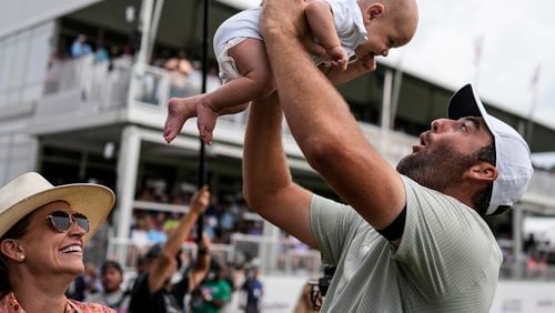 Scottie Scheffler holds his son Bennett Ezra Scheffler as his wife Meredith Scudder looks on on the 18th green after Scheffler won the final round of the Tour Championship golf tournament, Sunday, Sept. 1, 2024, in Atlanta. (AP Photo/Mike Stewart)