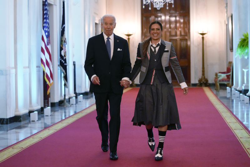 President Joe Biden walks with Ali Krieger, a member of the 2023 NWSL championship NJ/NY Gotham FC team, as they arrive for an event in the East Room of the White House in Washington, Monday, Sept. 23, 2024, to welcome the team and celebrate their championship. (AP Photo/Susan Walsh)