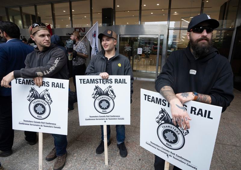 Rail workers picket in front of Canadian National headquarters on the first day of a nationwide rail shutdown, after workers were locked out by Canadian National and CPKC when new contract agreements weren't reached by the midnight deadline, in Montreal, Thursday, Aug. 22, 2024. (Ryan Remiorz /The Canadian Press via AP)