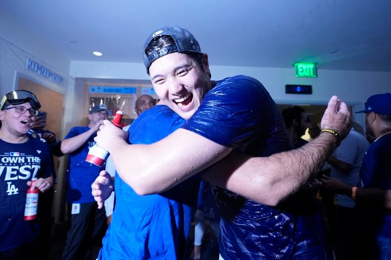 Los Angeles Dodgers designated hitter Shohei Ohtani hugs a teammate after the Dodgers defeated the San Diego Padres 7-2 in a baseball game to clinch the National League West division Thursday, Sept. 26, 2024, in Los Angeles. (AP Photo/Ashley Landis)