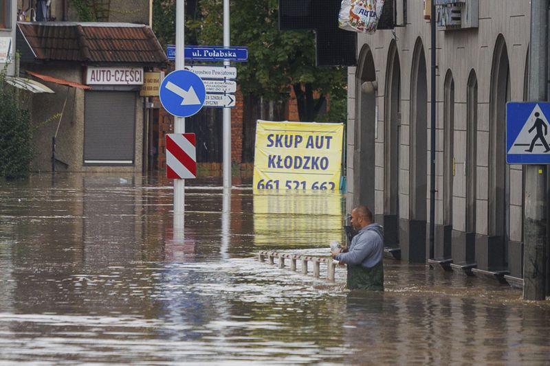 A man stands in waist-deep water that has flooded the streets and houses in the town of Kłodzko, in Poland's southwest, Sunday, Sept. 15, 2024, after days of unusually heavy rain. (AP Photo/Krzysztof Zatycki)