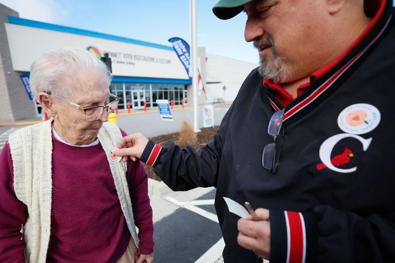 Bill Stephens puts a sticker to his 95-year-old mother, Arline Stephens after participating in early voting in Gwinnett County on Feb. 19, 2024. 