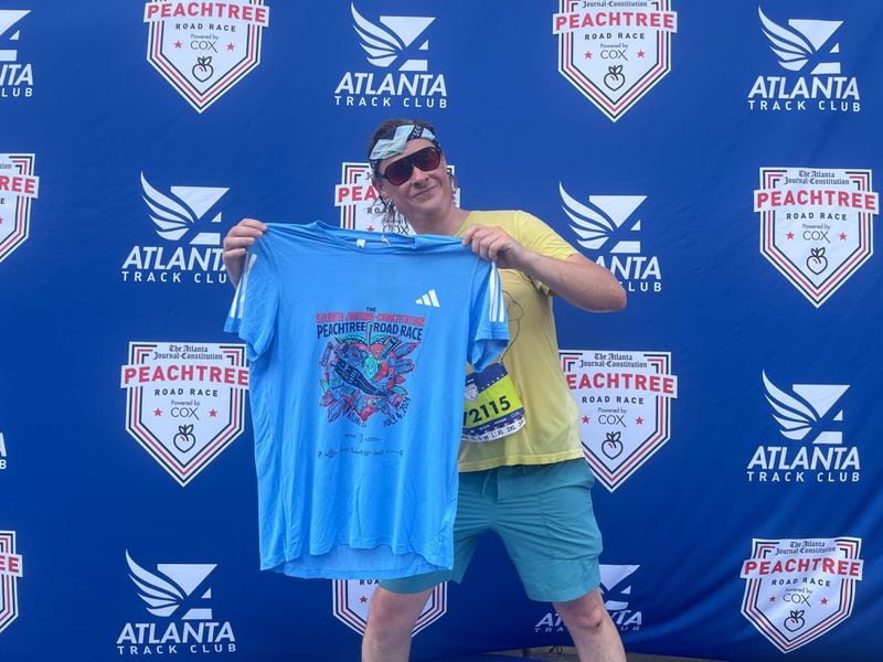 Atlanta Native Nick Benson holds up the AJC Peachtree Road Race T-shirt with his design. Benson won the T-shirt design contest.