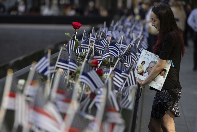 Mercedes Arias stands by the name of her father Joseph Amatuccio on the south pool during the 9/11 Memorial ceremony on the 23rd anniversary of the Sept. 11, 2001 attacks, Wednesday, Sept. 11, 2024, in New York. (AP Photo/Yuki Iwamura)