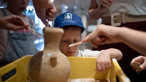 Ariel Heller, 4, helps to glue a broken clay jar during a special tour with his family after he accidentally broke another jar at the Reuben and Edith Hecht Museum in Haifa, Israel, Friday, Aug. 30, 2024. The boy who accidentally broke a rare 3,500-year-old jar in an Israeli museum has been forgiven and invited back, as curators hope to turn the disaster into a teachable moment. (AP Photo/Maya Alleruzzo)