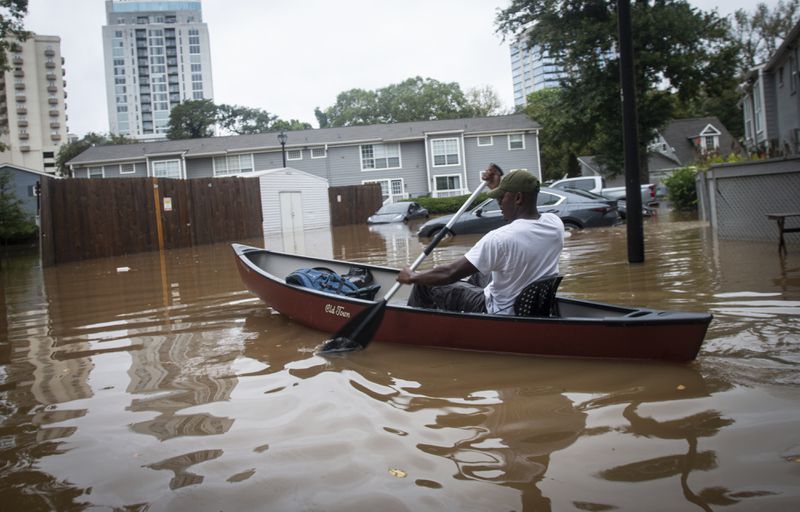 An unidentified man paddles a canoe to rescue residents and their belongings at a flooded apartment complex after Hurricane Helene passed the area on Friday, Sept. 27, 2024, in Atlanta. (AP Photo/Ron Harris)