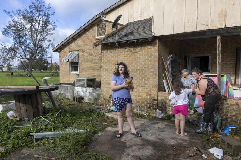 Bailee Boudreaux, 14, center, and her family bring out the chickens they let sleep in their house during the height of Hurricane Francine in Houma, La., Thursday, Sept. 12, 2024. (Chris Granger/The Times-Picayune/The New Orleans Advocate via AP)