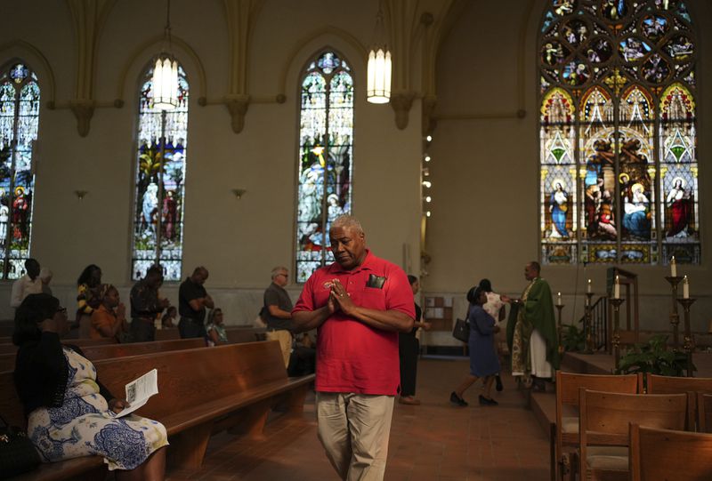 A parishioner walks back to his pew after taking Communion during a service in support of the Haitian community at St. Raphael Catholic church in Springfield, Ohio, Sunday, Sept. 15, 2024. (AP Photo/Luis Andres Henao)