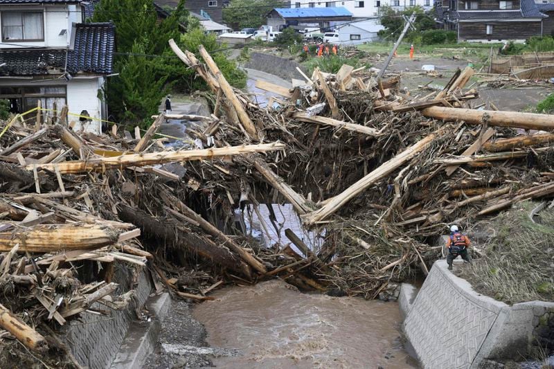 Debris and driftwoods are piled near damaged houses along a river running through Wajima, Japan, Monday, Sept. 23, 2024, following heavy rain in central Japan's Noto peninsula area, where a devastating earthquake took place on Jan. 1. (Tsuyoshi Ueda/Kyodo News via AP)