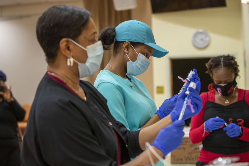 Registered nurses Ashanit Booker, center, and Arnita Dunwell prepare the COVID-19 vaccine shot during a vaccination event put on by the DeKalb County Board of Health and Delta Sigma Theta Sorority Inc. (Alyssa Pointer / Alyssa.Pointer@ajc.com)