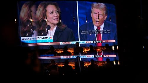 Reflected in a mirror, people watch the presidential debate between Republican presidential nominee former President Donald Trump and Democratic presidential nominee Vice President Kamala Harris, Tuesday, Sept. 10, 2024, at the Gipsy Las Vegas in Las Vegas. (AP Photo/John Locher)