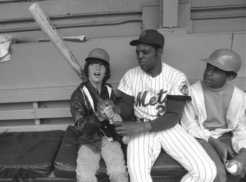 New York Mets' Willie Mays, center, shows John F. Kennedy Jr., left, the proper grip on the bat June 3, 1972, in the dugout at New York's Shea Stadium. At right is Eric Von Huguley, a friend who joined young John in a visit to the Mets' dugout before the game against the Atlanta Braves.  (AP Photo, File)