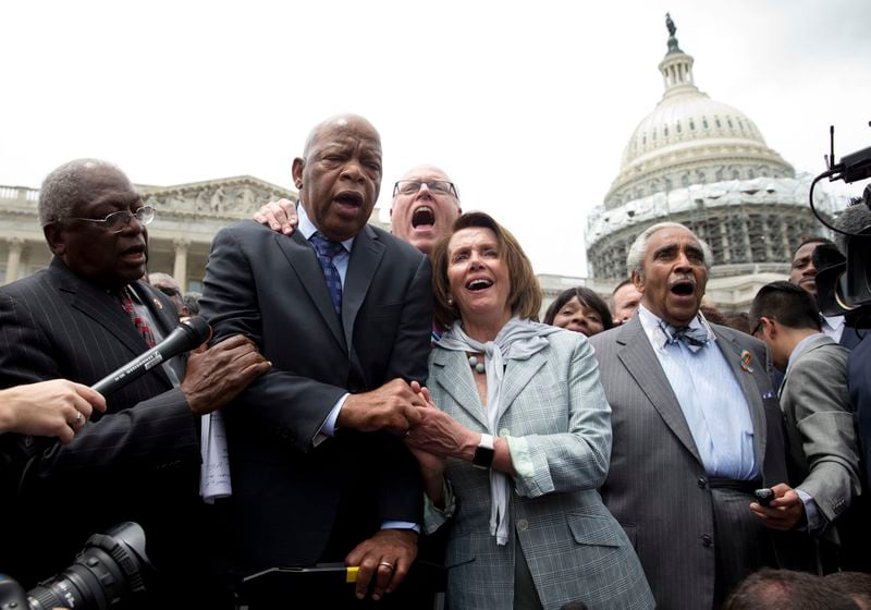 U.S. Rep. John Lewis, D-Atlanta, holds hands with House Minority Leader Nancy Pelosi of California as a group of congressmen sing “We Shall Overcome” on Capitol Hill in Washington after House Democrats ended their 26-hour sit-in protest in June. (AP Photo/Carolyn Kaster)