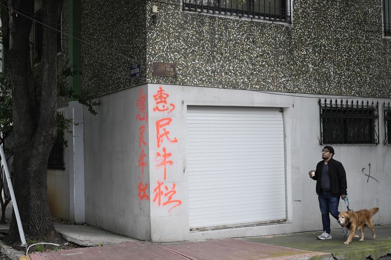 A man walks in front of a house with Chinese letters in Viaducto Piedad in Mexico City, Wednesday, July 24, 2024. (AP Photo/Eduardo Verdugo)