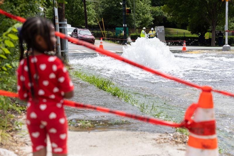 April Woods, 4, watches a water main break at Joseph E. Boone Boulevard and James P. Brawley Drive in Atlanta on Friday.