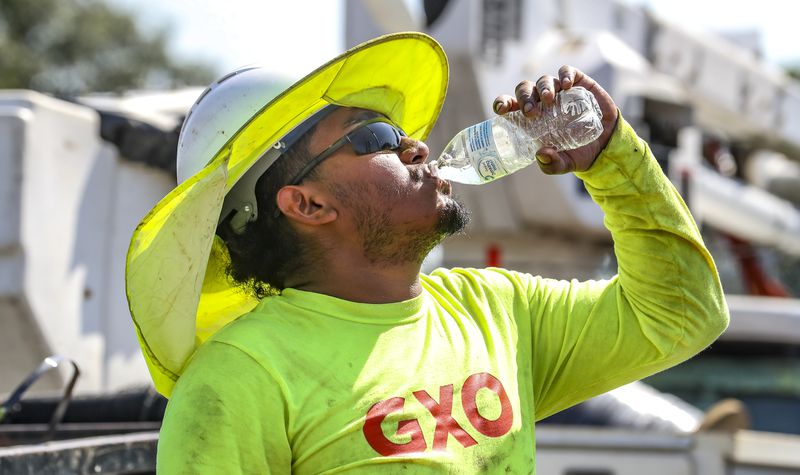 Fernando Rosales with RJH electrical contractors worked on installing an electrical box on Northside Drive near I-75 gets hydrated during the oppressive heat in metro Atlanta on Monday, Aug. 14, 2023. (John Spink / John.Spink@ajc.com)

