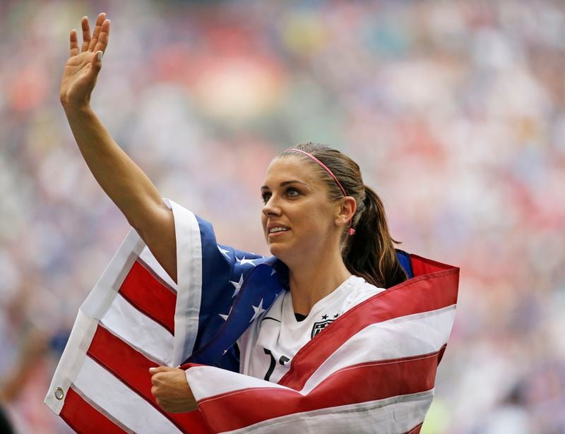 FILE - United States' Alex Morgan is draped in the U.S. flag as she waves to fans after the U.S. beat Japan 5-2 in the FIFA Women's World Cup soccer championship in Vancouver, British Columbia, Canada, Sunday, July 5, 2015. (AP Photo/Elaine Thompson, File)