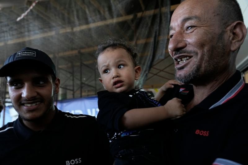 Ismail Al-Qadi, left, holds one of the sons of his brother, Kaid Farhan Al-Qadi, 52, who was held hostage by Hamas militants in the Gaza Strip, as they stand at the entrance of the Soroka Medical Center in Beersheba, Israel, Tuesday, Aug. 27, 2024. (AP Photo/Tsafrir Abayov)