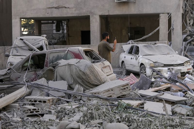 A man documents the damaged buildings at the site of an Israeli airstrike in Dahiyeh, Beirut, Lebanon, Thursday, Oct. 3, 2024. (AP Photo/Hassan Ammar)