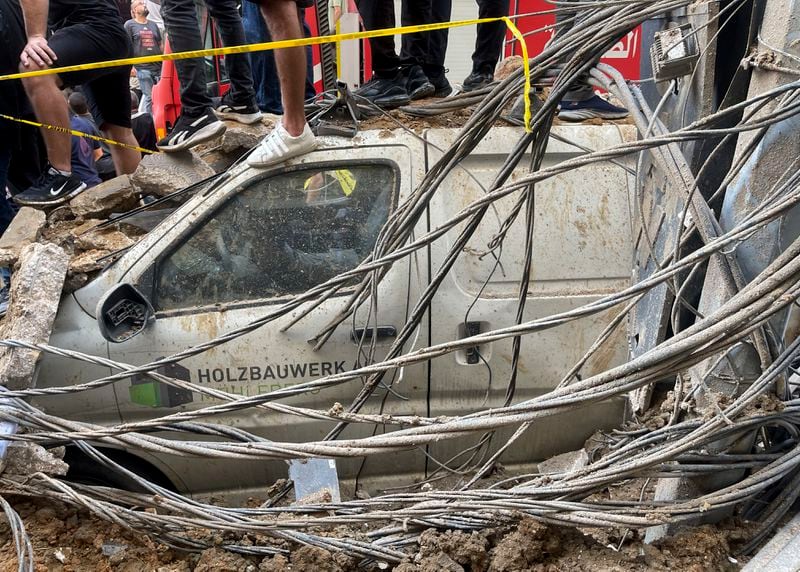 People stand on top of a damaged car at the scene of a missile strike in the southern suburbs of Beirut, Friday, Sept. 20, 2024. (AP Photo/Bilal Hussein)