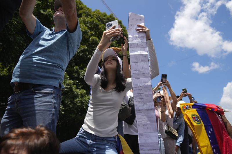 A woman holds up vote tally sheet during a rally to protest official results that declared President Nicolas Maduro the winner of the July presidential election, in Caracas, Venezuela, Saturday, Aug. 17, 2024. (AP Photo/Ariana Cubillos)