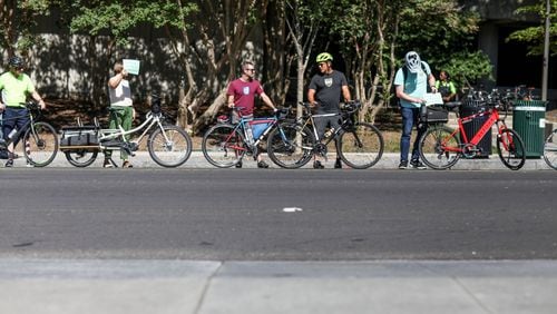 People form a line along West Peachtree Street near 15th Street on Wednesday, July 24, 2019, in Atlanta. The location is where William Alexander was hit and killed by a bus on July 17 while riding on an e-scooter. Organizers joined together as a “human protected sidewalk, bike and scooter lane” demanding the city prioritize protected bike and scooter lanes. BRANDEN CAMP/SPECIAL