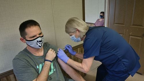 Elbert County High School teacher Richard Andrews received his second dose of the COVID-19 vaccine from Tina Mewborne, LPN, as his wife and teacher Tonya Andrews (background) looked at the Medical Center of Elberton on Wednesday, January 27, 2021.  (Hyosub Shin / Hyosub.Shin@ajc.com)