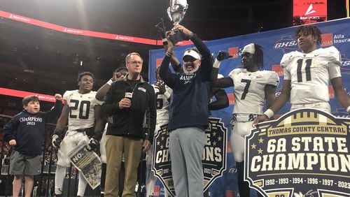 Thomas County Central head coach Justin Rogers accepts the championship trophy from GHSA executive Robin Hines after his teams 49-28 victory over Woodward Academy in the Class 6A final at Mercedes-Benz Stadium on Dec. 12, 2023.