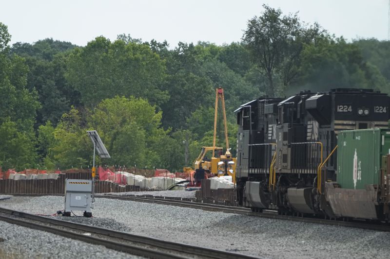 A Norfolk Southern freight train travels through the area where clean-up continues after a train carrying hazardous materials derailed more than a year ago, Tuesday, June 25, 2024, in East Palestine, Ohio. (AP Photo/Sue Ogrocki)